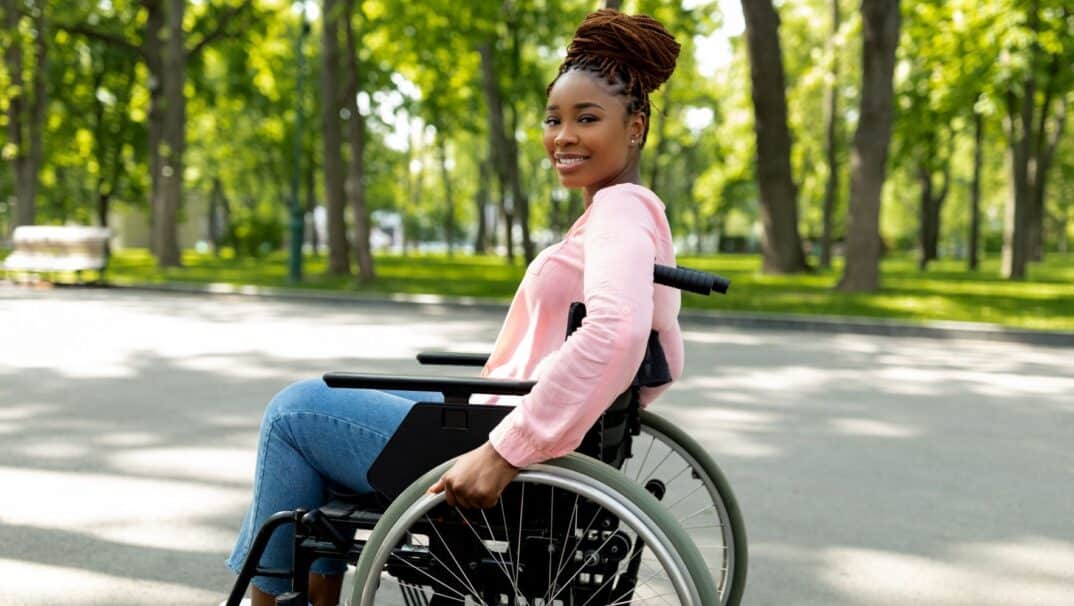 Black young adult in a wheelchair outside