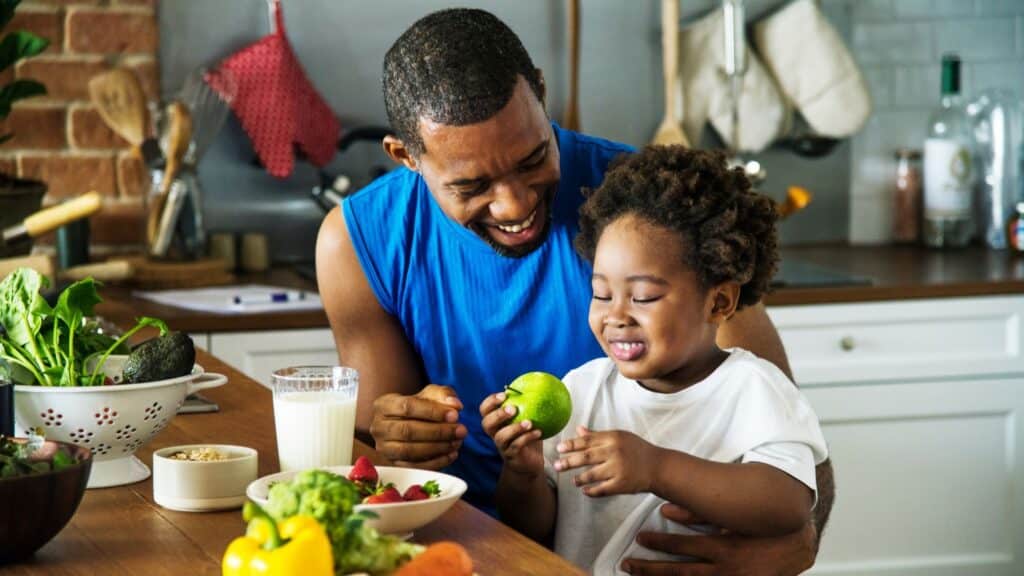 Father and young son prepping fruit and veggies in the kitchen