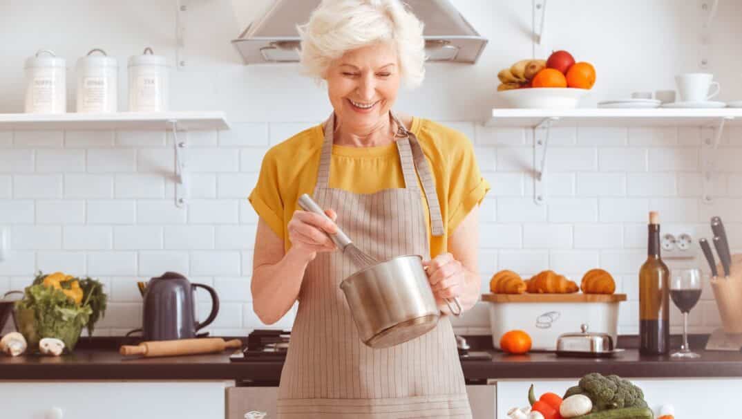 Middle-aged woman cooking in her kitchen. She is stirring a pot.