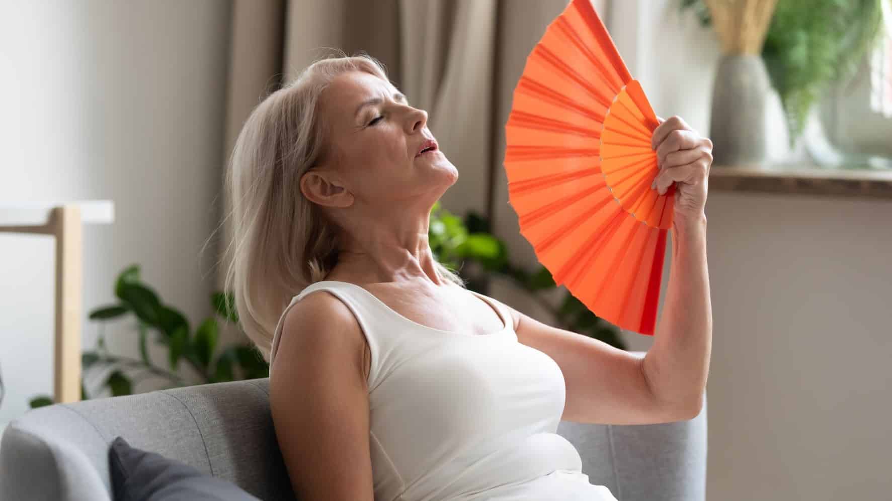 Woman over heating using a hand fan