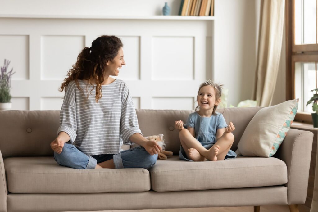 Mother and young daughter practicing mindfulness on a couch