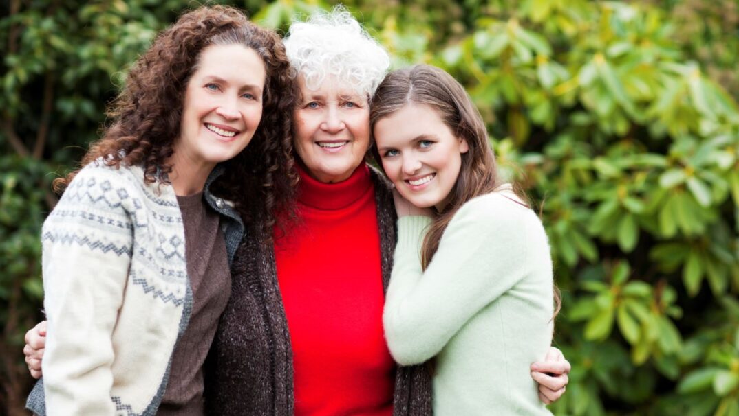 Three generations of women are posing together. The oldest is in the middle, with the daughter on the left and the granddaughter on the right.