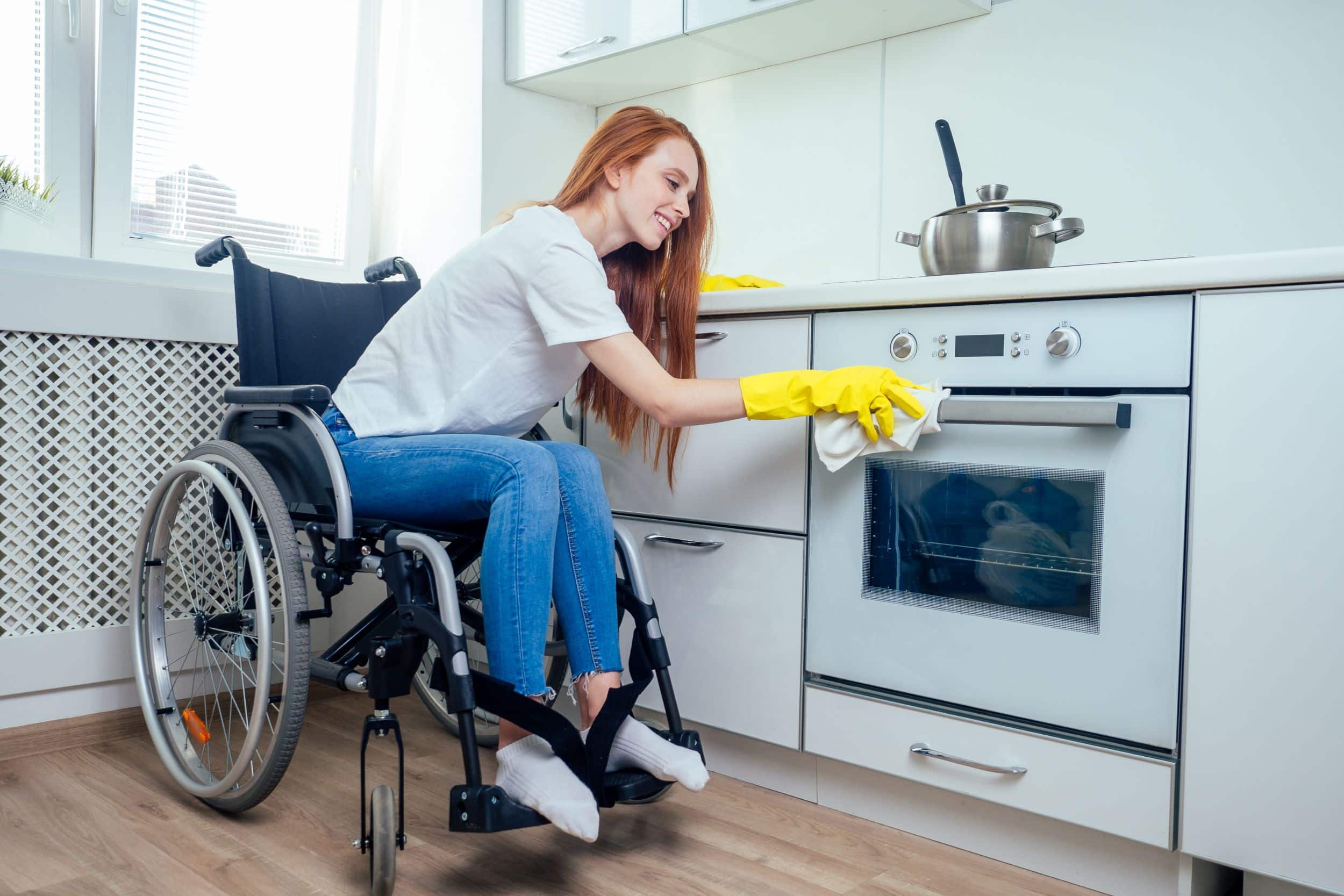 Young woman in wheelchair cleaning kitchen