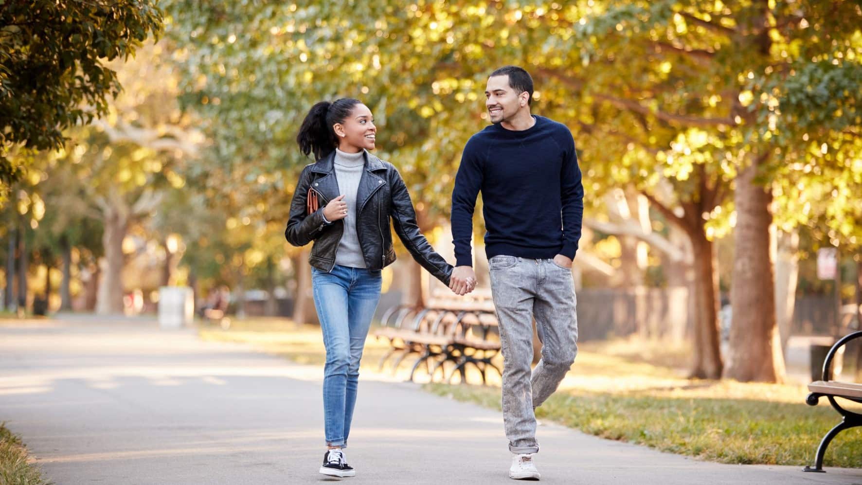 Young couple walking in a park while holding hands.