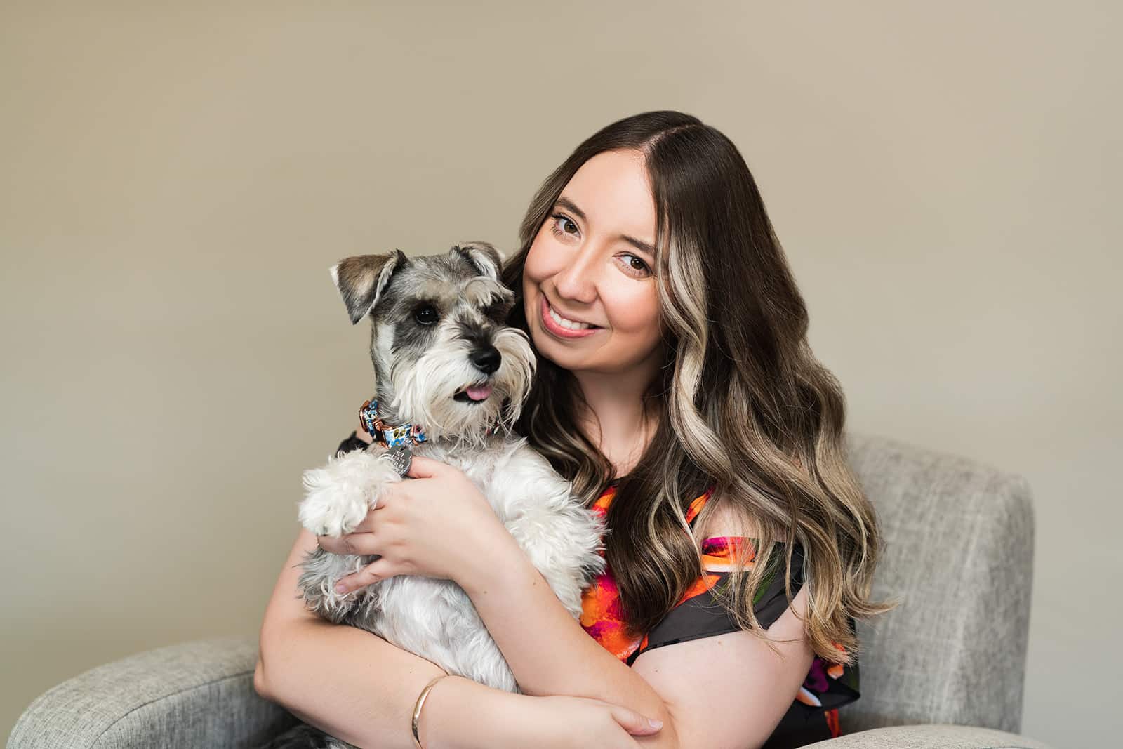 Young adult woman smiles with her schnauzer dog