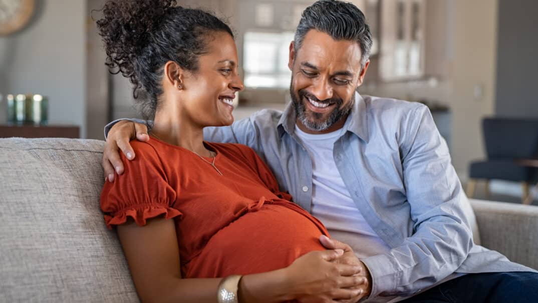 Pregnant Woman And Husband on Couch Smiling, MS and Pregnancy