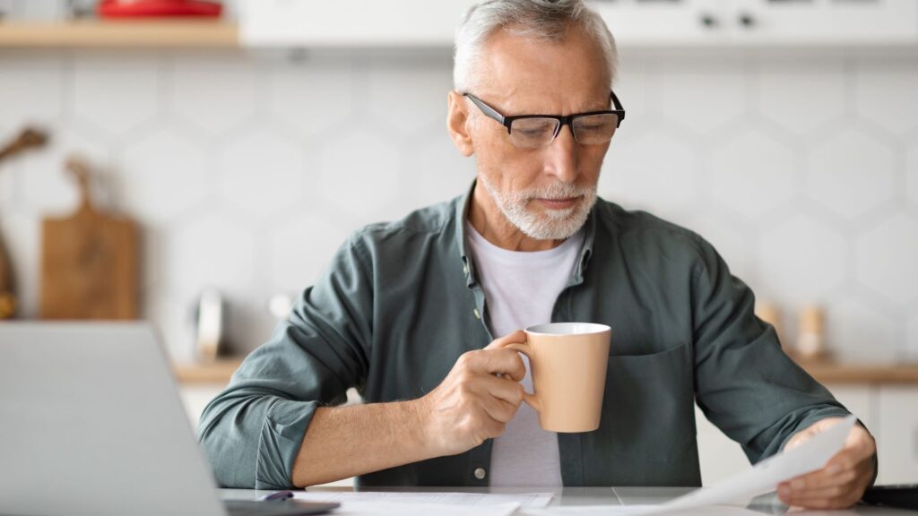Older Man drinking coffee and reading a paper