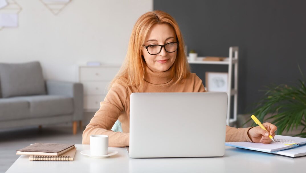 Woman on computer and writing on notebook
