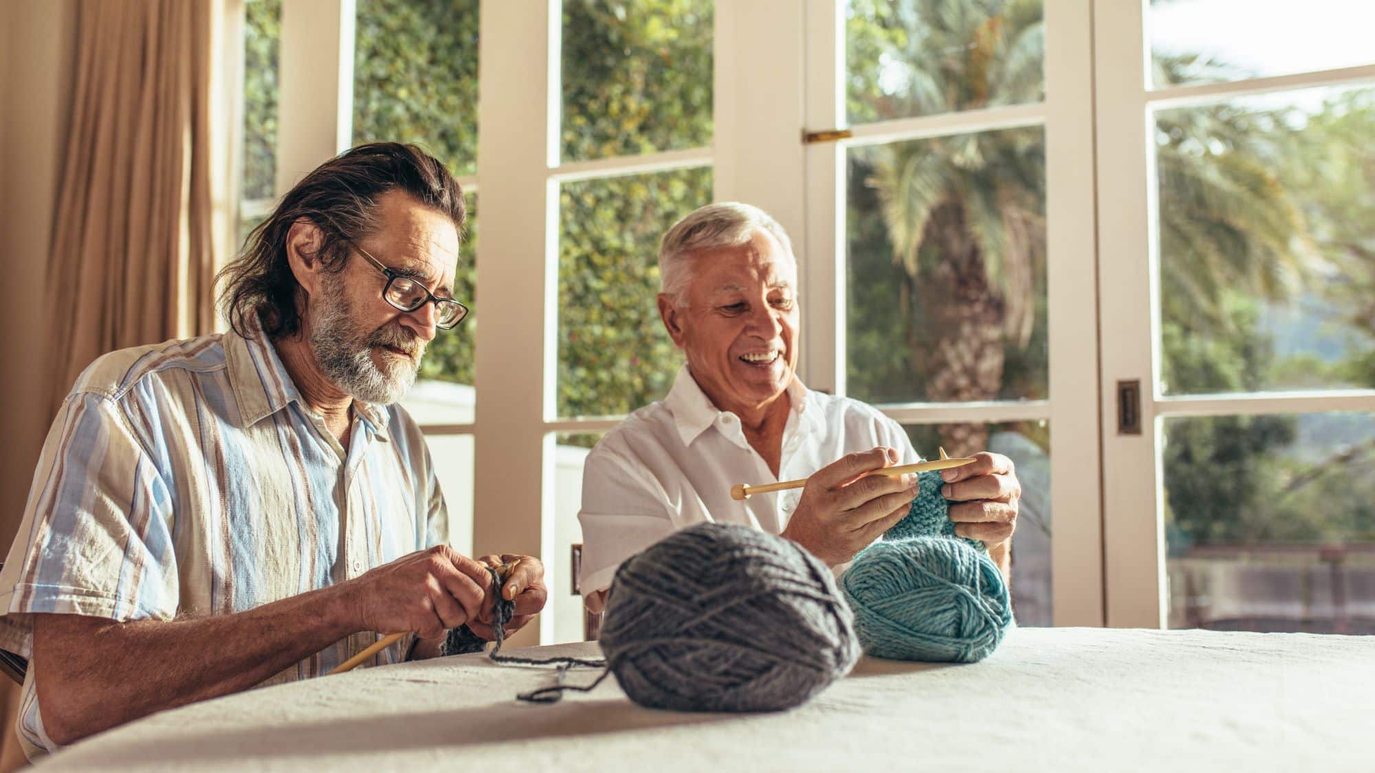 Two older men knitting together