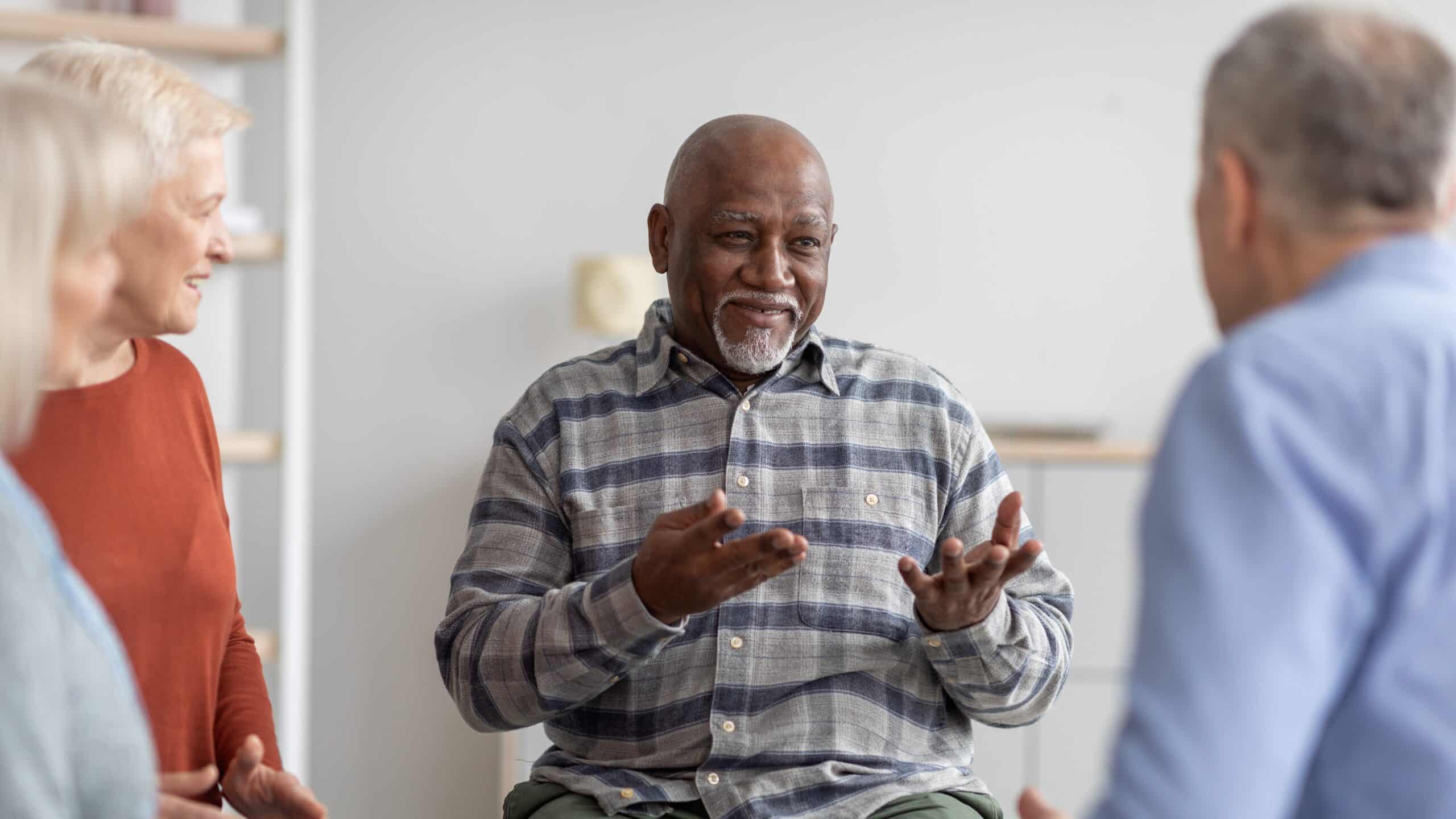 An older Black man speaking to a group of friends