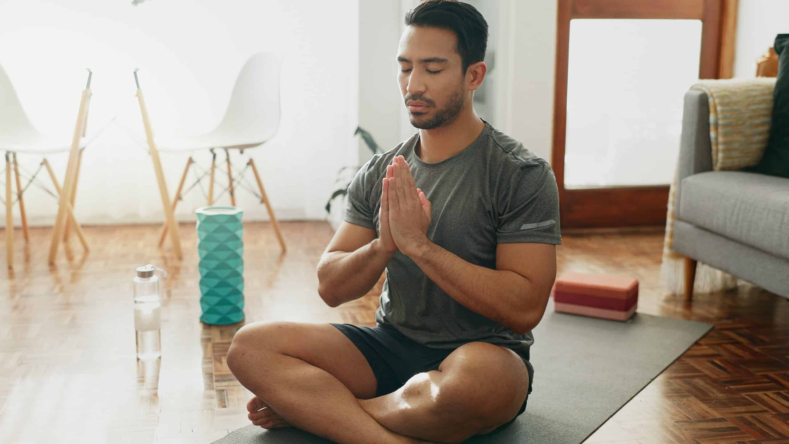 Hispanic man meditating by himself in his house.