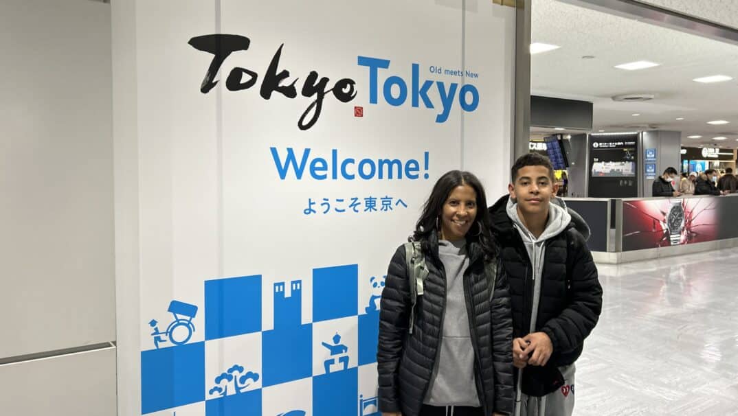 Dawn Morgan and her son next to a sign that says, "Welcome to Tokyo"