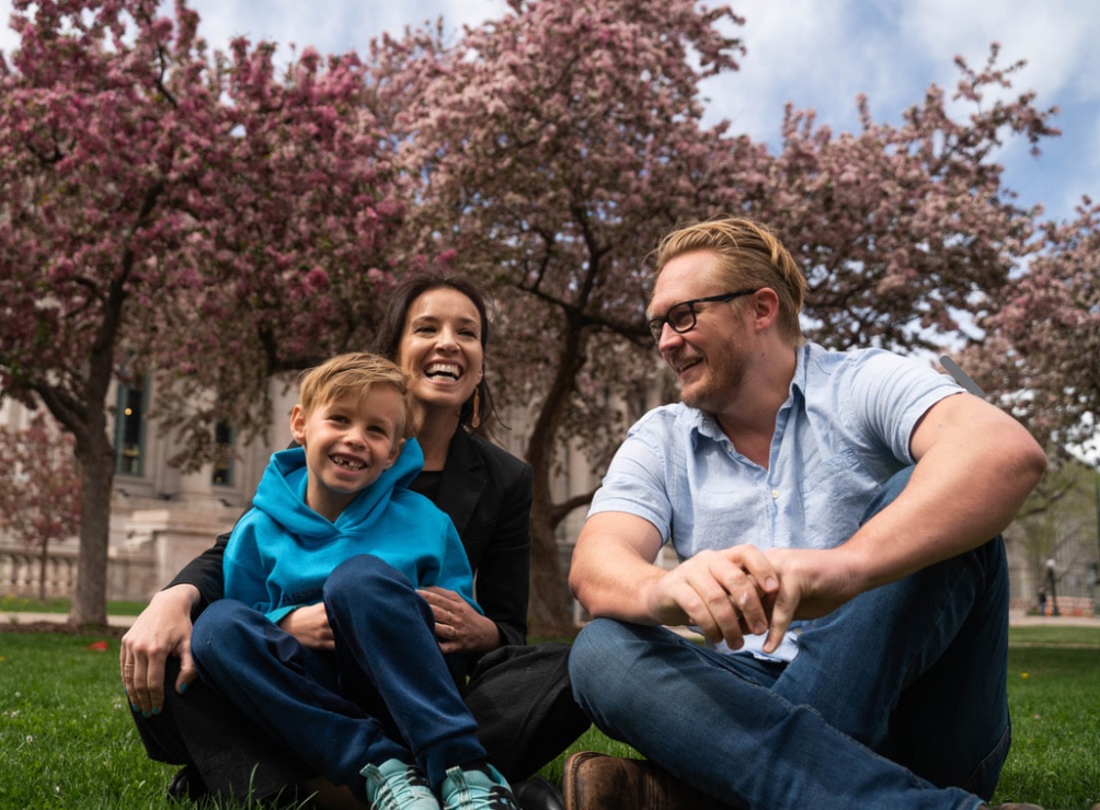 Julie, husband and son sitting in the grass