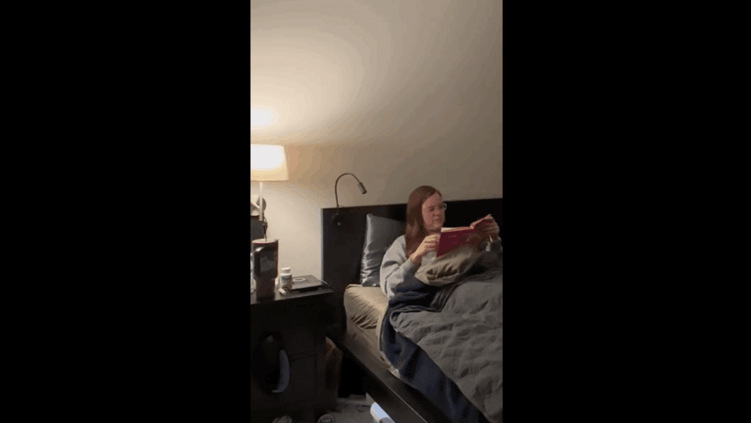 Emily Reilly sitting in bed reading a book.