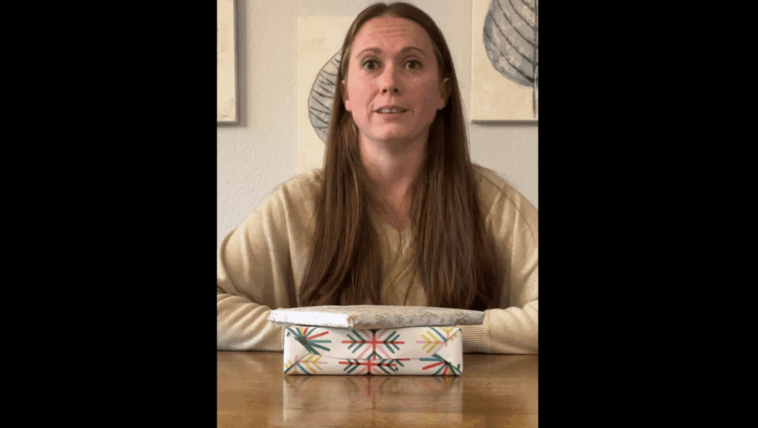 Stephanie Nolan sitting with presents on a table in front of her.