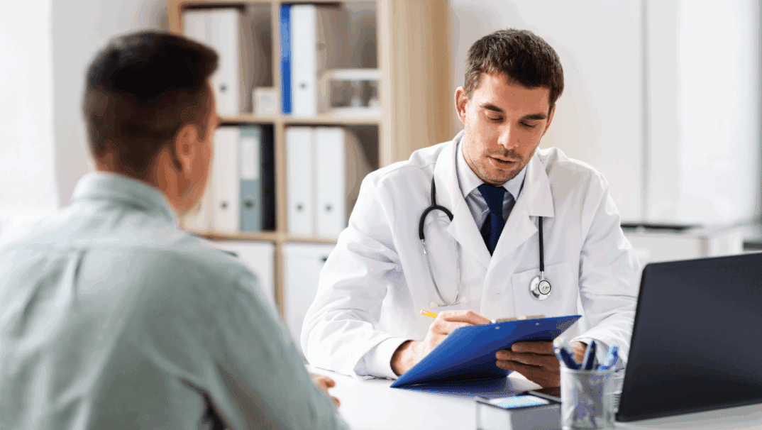 Male doctor reading something off a tablet to a patient