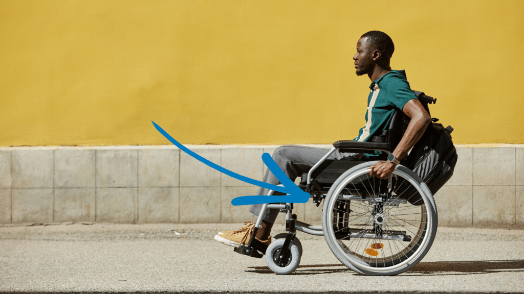 A young Black man using his wheelchair outside.