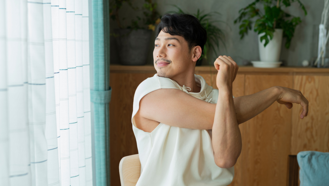 Asian Man Sits and Stretches his arm.