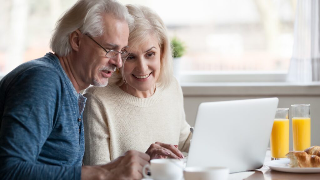 Middle Aged Couple Sitting At Laptop Together
